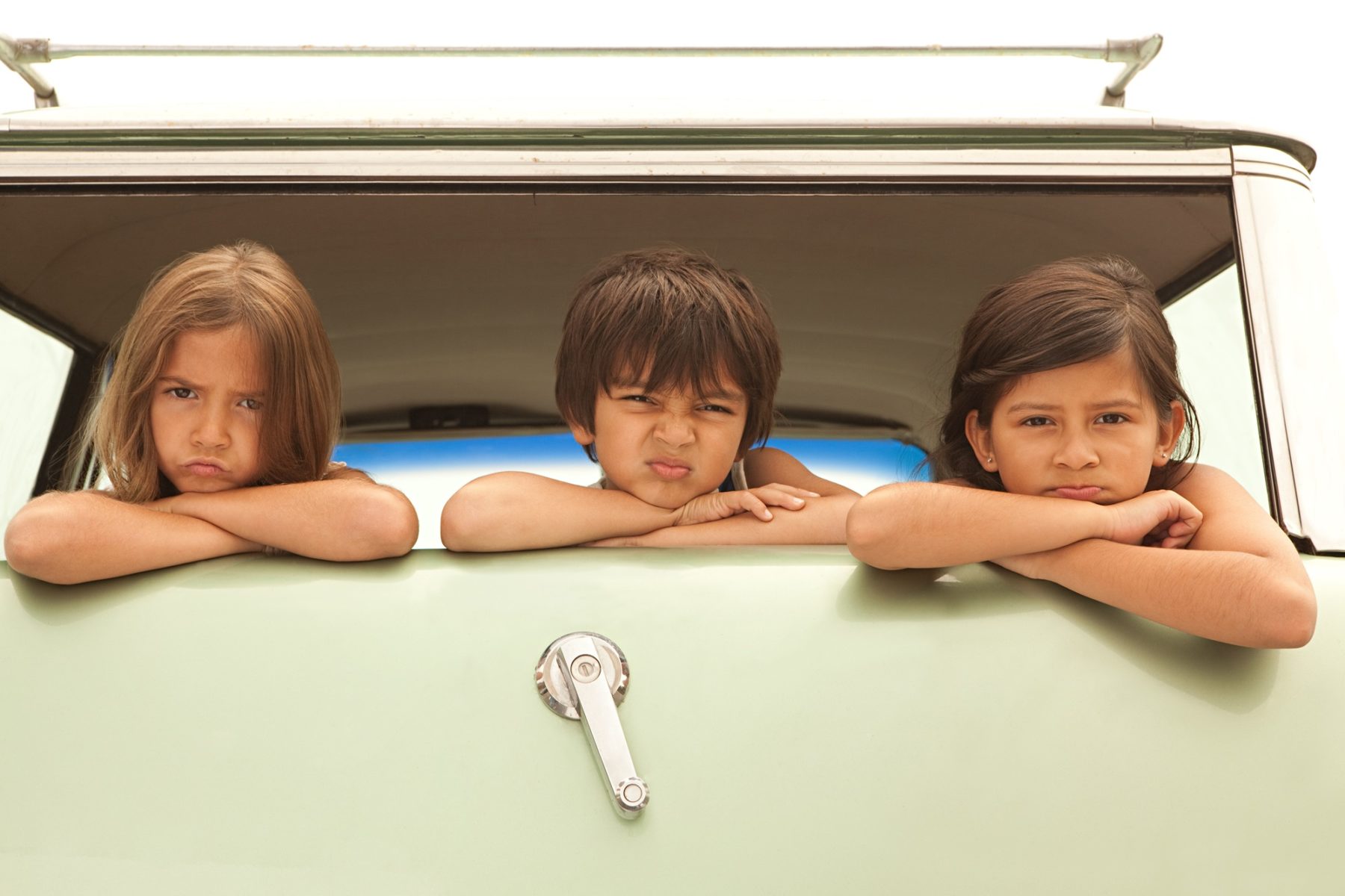 Des enfants boudent à l'arrière d'une voiture